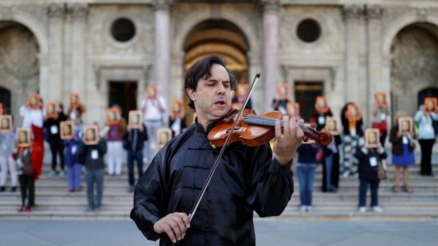 A violonist performs during an action by Paris tour guides at Le Louvre museum courtyard to warn on their working conditions in Paris as the museum reopens its doors to the public after almost 4-month closure due to the coronavirus disease (COVID-19) outbreak in France, July 6, 2020. (REUTERS)