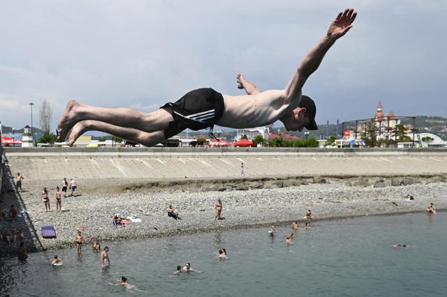 A boy jumps into water as other people enjoy the beach in the Black Sea resort of Sochi, Russia, Sunday, July 5, 2020. (AP)