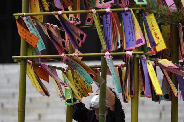 A visitor attaches paper strips with her wish written on it for the Star Festival or "Tanabata" to a bamboo branch at a temple. (AP Photo/Eugene Hoshiko) A visitor attaches paper strips with her wish written on it for the Star Festival or "Tanabata" to a bamboo branch at a temple. (AP Photo/Eugene Hoshiko)