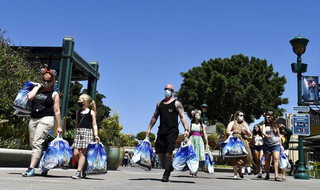Visitors to the Disneyland Resort head toward the exit after a morning of shopping on the reopening day of the Downtown Disney District on its reopening day in Anaheim, Calif., Thursday, July 9, 2020. (AP) Visitors to the Disneyland Resort head toward the exit after a morning of shopping on the reopening day of the Downtown Disney District on its reopening day in Anaheim, Calif., Thursday, July 9, 2020. (AP)