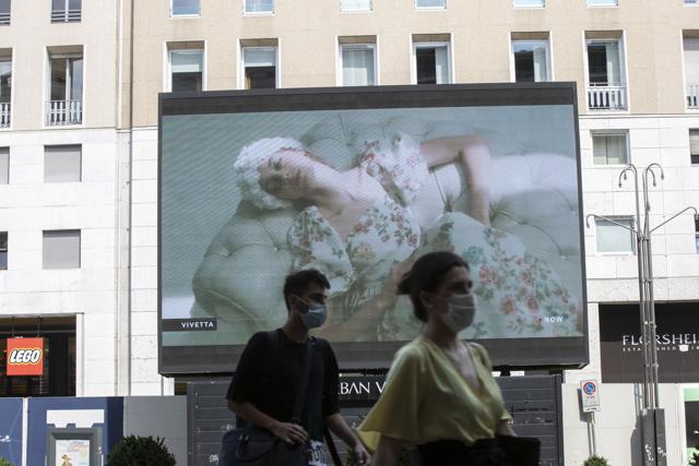 Pedestrians pass by a screen showing a Vivetta model during the Milan Digital Fashion Week, in Milan, Italy. (AP Photo/Luca Bruno) Pedestrians pass by a screen showing a Vivetta model during the Milan Digital Fashion Week, in Milan, Italy. (AP Photo/Luca Bruno)