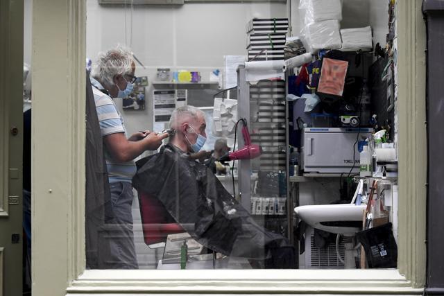 A hairdresser works wearing a protective mask, in London, Saturday, July 4, 2020. (AP) A hairdresser works wearing a protective mask, in London, Saturday, July 4, 2020. (AP)