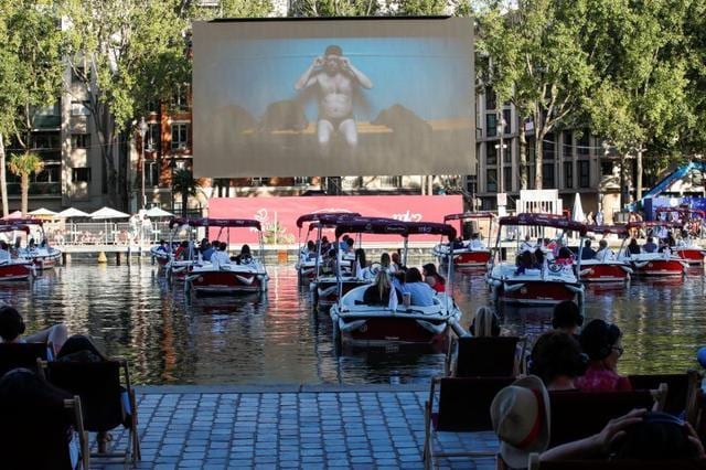 People watch the film Le Grand Bain seat on beach chairs and from boats at the Cinema on the water (Cinema sur l’eau) as a floating cinema with 38 socially-distant electric boats kicks off the Paris Plages summer event along the Bassin de la Villette, in Paris following the outbreak of the coronavirus disease (COVID-19) in France. (REUTERS/Gonzalo Fuentes) People watch the film Le Grand Bain seat on beach chairs and from boats at the Cinema on the water (Cinema sur l’eau) as a floating cinema with 38 socially-distant electric boats kicks off the Paris Plages summer event along the Bassin de la Villette, in Paris following the outbreak of the coronavirus disease (COVID-19) in France. (REUTERS/Gonzalo Fuentes)
