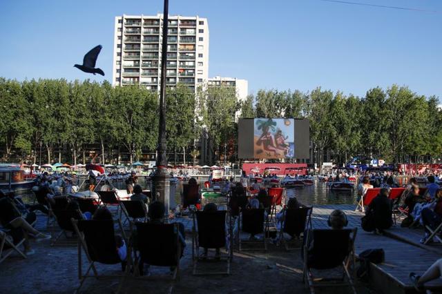 People watch the film Le Grand Bain seat on beach chairs and from boats at the Cinema on the water (Cinema sur l’eau) as a floating cinema with 38 socially-distant electric boats kicks off the Paris Plages summer event along the Bassin de la Villette, in Paris following the outbreak of the coronavirus disease (COVID-19) in France July 18, 2020. (REUTERS/Gonzalo Fuentes) People watch the film Le Grand Bain seat on beach chairs and from boats at the Cinema on the water (Cinema sur l’eau) as a floating cinema with 38 socially-distant electric boats kicks off the Paris Plages summer event along the Bassin de la Villette, in Paris following the outbreak of the coronavirus disease (COVID-19) in France July 18, 2020. (REUTERS/Gonzalo Fuentes)