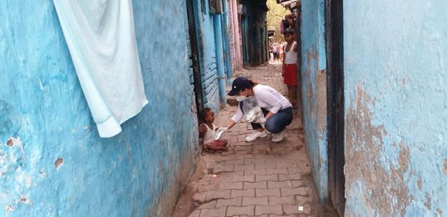 A volunteer of Anything Will Do organisation giving milk packet to a kid A volunteer of Anything Will Do organisation giving milk packet to a kid