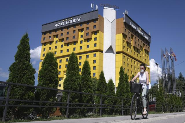 A woman rides a bicycle passing the Holiday Hotel in Sarajevo, Bosnia, Wednesday, July 29, 2020. (AP) A woman rides a bicycle passing the Holiday Hotel in Sarajevo, Bosnia, Wednesday, July 29, 2020. (AP)