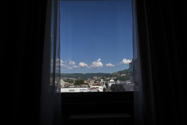 A window in one of the rooms of The Holiday Hotel, which opened as Holiday Inn, a luxurious accommodation for world's royalty, film stars and other dignitaries who came to watch the 1984 Winter Olympics, and less than a decade later, became ground zero of the bloody siege of Sarajevo in the 1990's, offers a view of Sarajevo, Bosnia, Wednesday, July 29, 2020. (AP) A window in one of the rooms of The Holiday Hotel, which opened as Holiday Inn, a luxurious accommodation for world's royalty, film stars and other dignitaries who came to watch the 1984 Winter Olympics, and less than a decade later, became ground zero of the bloody siege of Sarajevo in the 1990's, offers a view of Sarajevo, Bosnia, Wednesday, July 29, 2020. (AP)
