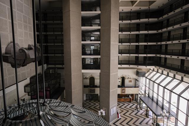 A man walks in the lobby of the Holiday Hotel, which opened as Holiday Inn, a luxurious accommodation for world's royalty, film stars and other dignitaries who came to watch the 1984 Winter Olympics, and less than a decade later, became ground zero of the bloody siege of Sarajevo in the 1990's, in Sarajevo, Bosnia, Wednesday, July 29, 2020. (AP) A man walks in the lobby of the Holiday Hotel, which opened as Holiday Inn, a luxurious accommodation for world's royalty, film stars and other dignitaries who came to watch the 1984 Winter Olympics, and less than a decade later, became ground zero of the bloody siege of Sarajevo in the 1990's, in Sarajevo, Bosnia, Wednesday, July 29, 2020. (AP)