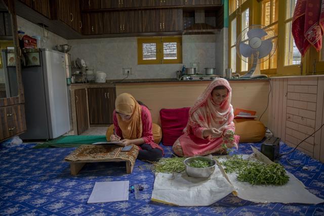 Kashmiri student Aaishya Imtiyaz writes her examination as her mother Nusrat Fatima cleans vegetables inside their kitchen in Srinagar, Indian controlled Kashmir, Wednesday, July 22, 2020. Experts say lack of formal schooling during the lockdown could have a serious psychological and emotional impact on the children. With no opportunity to be with friends, many homebound students are struggling to reimagine the school experience as parents take over the role of teachers. "This is my second exam at home since last year. I hope and pray that we go to school very soon," Aaishya said. (AP) Kashmiri student Aaishya Imtiyaz writes her examination as her mother Nusrat Fatima cleans vegetables inside their kitchen in Srinagar, Indian controlled Kashmir, Wednesday, July 22, 2020. Experts say lack of formal schooling during the lockdown could have a serious psychological and emotional impact on the children. With no opportunity to be with friends, many homebound students are struggling to reimagine the school experience as parents take over the role of teachers. "This is my second exam at home since last year. I hope and pray that we go to school very soon," Aaishya said. (AP)