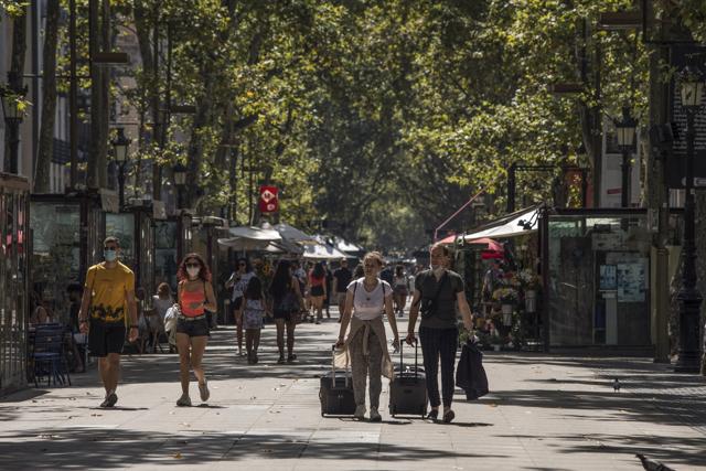 Tourists wheel luggage down Las Ramblas in Barcelona, Spain, on Saturday, Aug. 1, 2020. (Bloomberg)