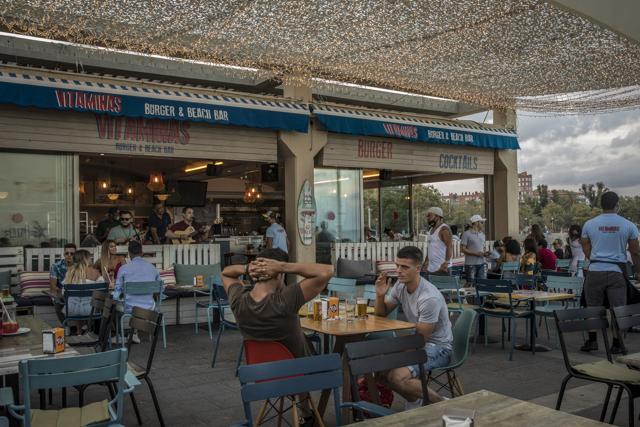 Customers sit at tables in the outdoor terrace area of a bar in the Moll de Gregal area of Barcelona, Spain on Sunday, Aug. 2, 2020. (Bloomberg) Customers sit at tables in the outdoor terrace area of a bar in the Moll de Gregal area of Barcelona, Spain on Sunday, Aug. 2, 2020. (Bloomberg)