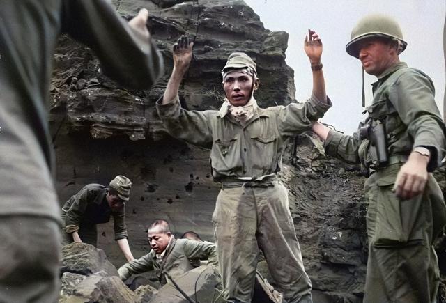 In this black and white photo digitally colorized and published in 2020 by Anju Niwata and Hidenori Watanave, the first of 20 Japanese emerges from an Iwo Jima cave, with his hands in the air, on April 5, 1945. (AP) In this black and white photo digitally colorized and published in 2020 by Anju Niwata and Hidenori Watanave, the first of 20 Japanese emerges from an Iwo Jima cave, with his hands in the air, on April 5, 1945. (AP)