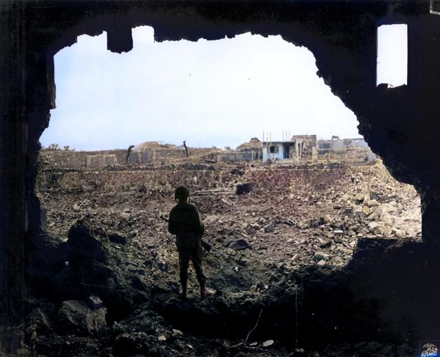 In this black and white photo provided by the U.S. Marine Corps and digitally colorized and published in 2020 by Anju Niwata and Hidenori Watanave, a Marine rifleman views the result of the American bombardment of Naha, on Okinawa, June 13, 1945. (AP) In this black and white photo provided by the U.S. Marine Corps and digitally colorized and published in 2020 by Anju Niwata and Hidenori Watanave, a Marine rifleman views the result of the American bombardment of Naha, on Okinawa, June 13, 1945. (AP)
