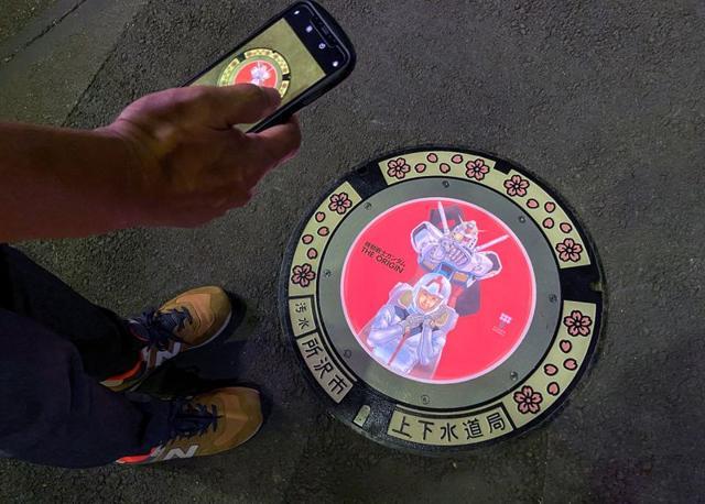 A passerby using a smartphone takes a photo of an illuminated manhole cover. (REUTERS) A passerby using a smartphone takes a photo of an illuminated manhole cover. (REUTERS)