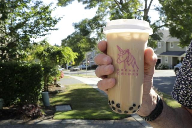 Greg Schwab holds a boba tea he ordered from the Dreamy Drinks food truck, Monday, Aug. 10, 2020, near the suburb of Lynnwood, Wash., north of Seattle. In June, Greg's wife Julie Schwab started organizing a regular schedule to bring food trucks to their neighbourhood as a way to both help small businesses and give families staying at home during the coronavirus pandemic different options for meals. (AP)