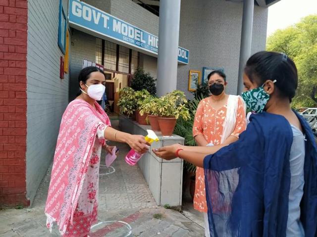 A teacher administering hand sanitiser as students returned to school after six months due to the Covid-19 pandemic. (Keshav Singh/HT) A teacher administering hand sanitiser as students returned to school after six months due to the Covid-19 pandemic. (Keshav Singh/HT)
