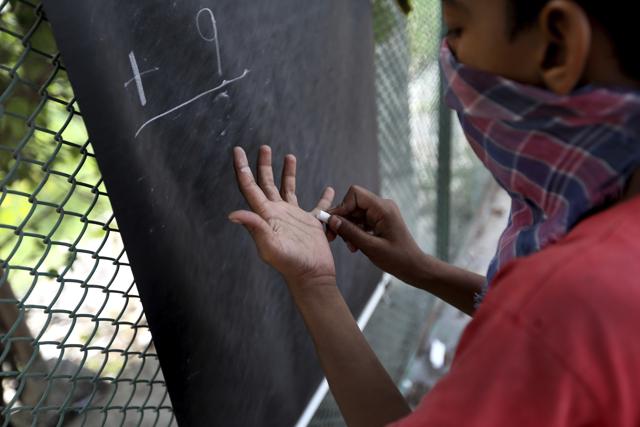 A boy learns addition on a sidewalk class taught by an Indian couple, Veena Gupta and her husband Virendra Gupta, in New Delhi, India, on Sept. 3, 2020. (AP) A boy learns addition on a sidewalk class taught by an Indian couple, Veena Gupta and her husband Virendra Gupta, in New Delhi, India, on Sept. 3, 2020. (AP)