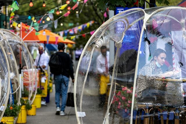 A woman sits outside Cafe Du Soleil under bubble tents. (REUTERS)