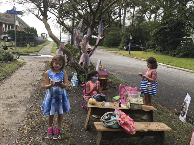Maya Gebler, center, Cate and Sophie Carroll , right, write letters to fairies in Norfolk, Virginia on Monday Oct. 12, 2020. (AP)