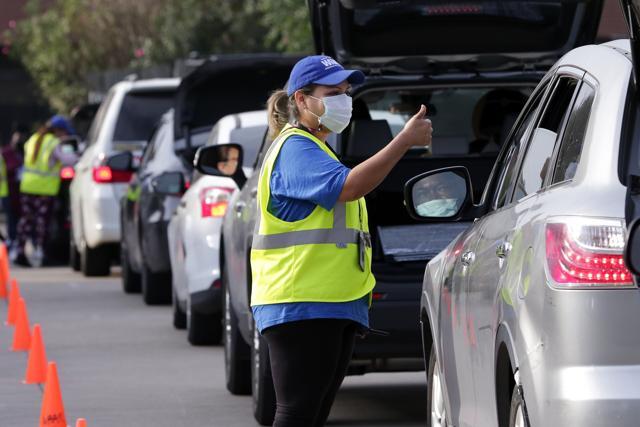 Lisa Iparrea, director of client services, gives a thumbs up as she helps direct cars through the touchless drive thru food distribution line at the West Houston Assistance Ministries Wednesday, Oct. 14, 2020, in Houston. (AP) Lisa Iparrea, director of client services, gives a thumbs up as she helps direct cars through the touchless drive thru food distribution line at the West Houston Assistance Ministries Wednesday, Oct. 14, 2020, in Houston. (AP)