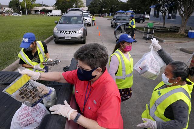 Volunteers load bags of food into the bed of a client's pick up truck in the drive thru line at the West Houston Assistance Ministries. (AP) Volunteers load bags of food into the bed of a client's pick up truck in the drive thru line at the West Houston Assistance Ministries. (AP)