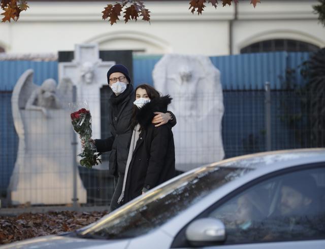 A couple walk by a cemetry holding flowers, after Poland's government closed all cemeteries in an attempt to curb the spread of COVID-19, in Warsaw, Poland. (AP) A couple walk by a cemetry holding flowers, after Poland's government closed all cemeteries in an attempt to curb the spread of COVID-19, in Warsaw, Poland. (AP)