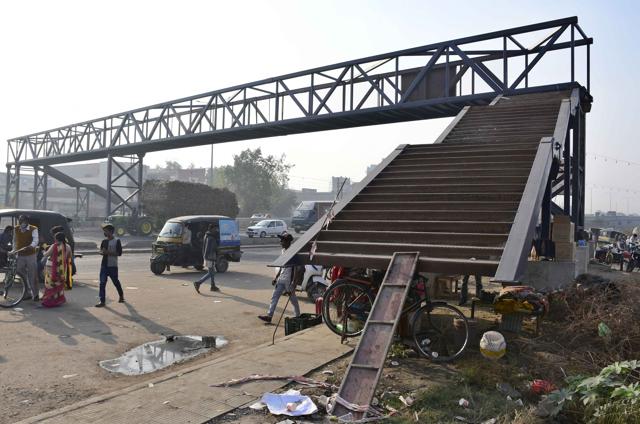 The staircase of the overbridge visible behind them has yet to be connected to the road to allow public to use it. (Harsimar Pal Singh/HT)