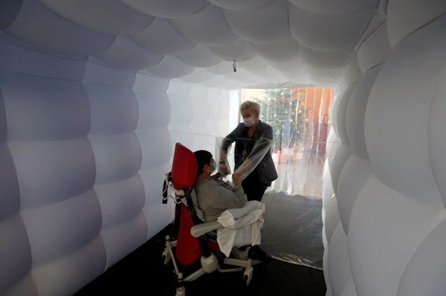 Raymonde holds the hands of her daughter Fabienne behind a removable plastic sheet. (REUTERS) Raymonde holds the hands of her daughter Fabienne behind a removable plastic sheet. (REUTERS)