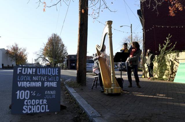 Mary Jane D'arville plays the harp while Marlysse Simmons and son Desi Alvarez, 2, listen outside of Frank Pichel's tree lot. (AP) Mary Jane D'arville plays the harp while Marlysse Simmons and son Desi Alvarez, 2, listen outside of Frank Pichel's tree lot. (AP)
