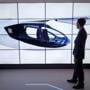 A man poses alongside screens presenting the Rolls-Royce EVTOL air taxi concept during the Farnborough Airshow.