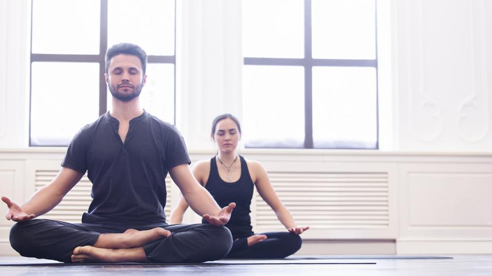 Young fit Black woman in seated balancing yoga pose exercising on