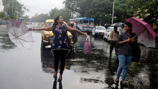 கொல்கத்தாவில் மழையில் நனைந்த படி செல்லும் இளம்பெண்கள்