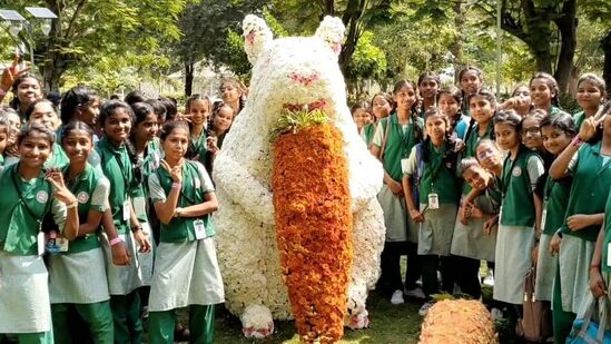மலர்களால் வடிவமைக்கப்பட்ட முயலுடன் பள்ளி குழந்தைகள் புகைப்படம் எடுக்கும் காட்சி