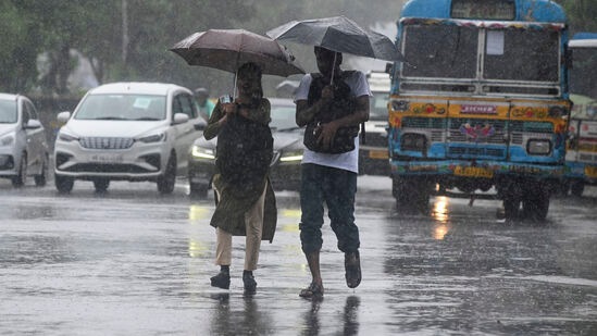 ஞாயிற்றுக்கிழமை ரெமல் சூறாவளி நிலச்சரிவுக்கு முன்னதாக கொல்கத்தாவில் பயணிகள் மழையின் போது சாலைகளைக் கடக்கும்போது குடையுடன் சென்ற நபர்கள்.