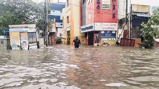 தேங்கிய மழை நீரில் நடந்து வரும் நபர்
