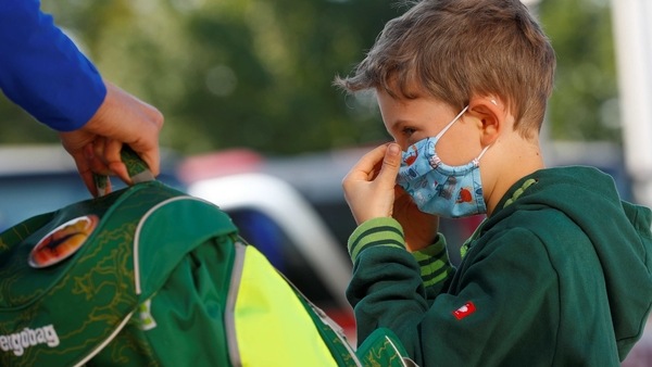 A boy adjusts his protective face mask outside a primary school, as Austrian schools reopen for pupils aged roughly six to 14, during the global coronavirus disease (COVID-19) outbreak, in Brunn am Gebirge, Austria May 18, 2020. REUTERS/Leonhard Foeger