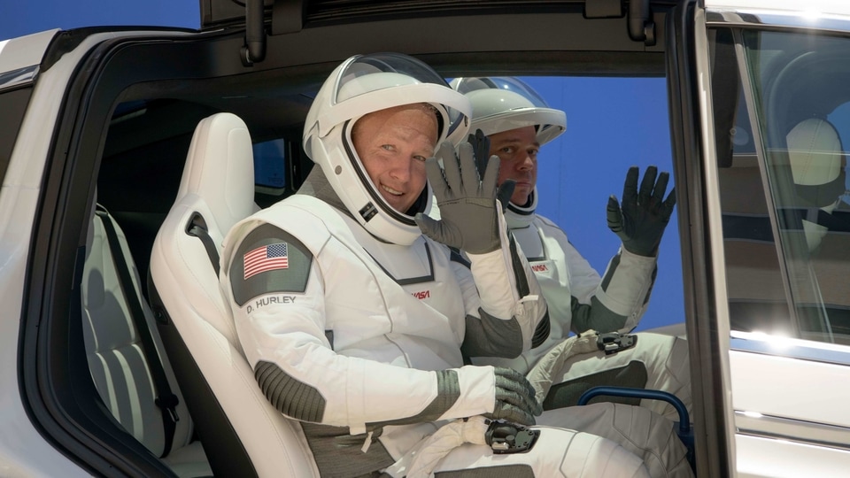 NASA astronauts Douglas Hurley (left) and Robert Behnken, wearing SpaceX spacesuits, depart the Neil A. Armstrong Operations and Checkout Building for Launch Complex 39A during a dress rehearsal prior to the Demo-2 mission launch, 