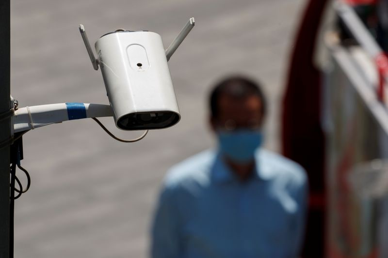 A CCTV security surveillance camera overlooks a street as a man walks past following the spread of the coronavirus disease (COVID-19) in Beijing,&nbsp;