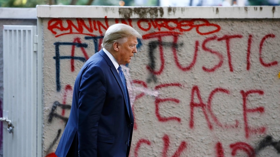 President Donald Trump walks from the White House past graffiti in Lafayette Park to visit St. John's Church in Washington on Monday, June 1, 2020.