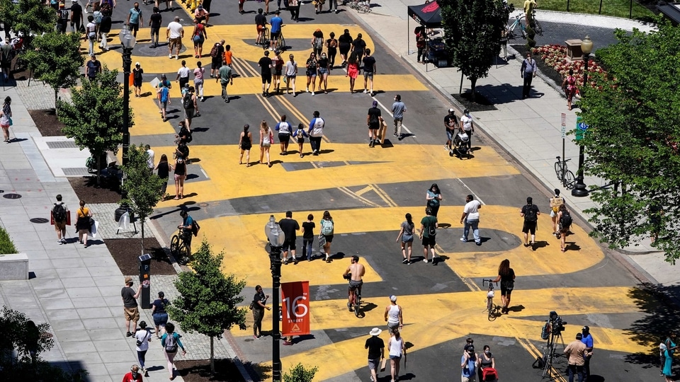 People walk on a Black Lives Matter sign painted on the street as they protest the death in Minneapolis police custody of George Floyd, near the White House in Washington, U.S., June 7, 2020. REUTERS/Joshua Roberts