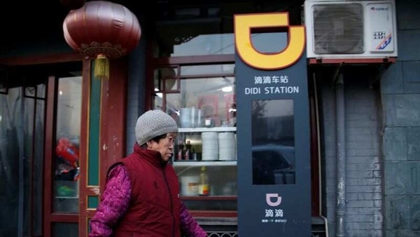 A woman walks past a sign of station for Didi Chuxing in Beijing, China.