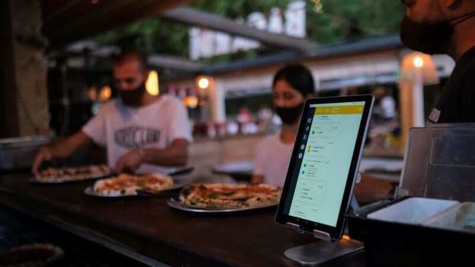 Employees pick up the pizzas near an IPad with the 
