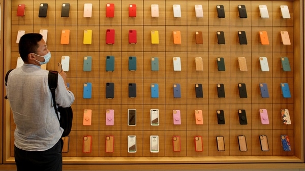 A man stands in front of a wall of iPhones cases in the new Apple flagship store on its opening day following an outbreak of the coronavirus disease (Covid-19) in Sanlitun in Beijing, China. 