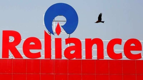A bird flies past a Reliance Industries sign in Ahmedabad, India.