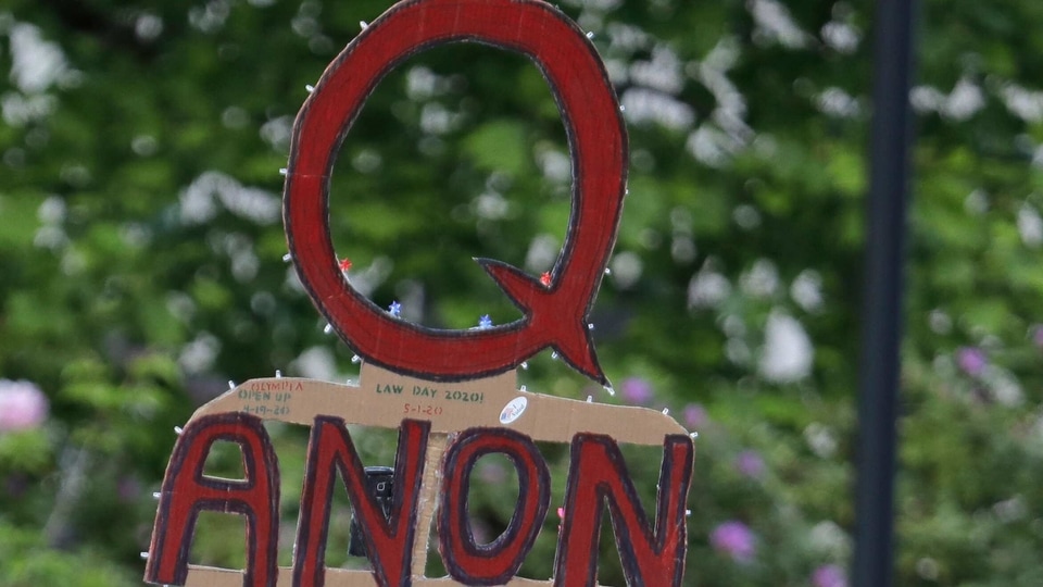 In this May 14, 2020, file photo, a person carries a sign supporting QAnon at a protest rally in Olympia, Wash. Facebook said Tuesday, Oct. 6, 2020, that it will remove Facebook pages, groups and Instagram accounts for “representing QAnon.” (AP Photo/Ted S. Warren, File)