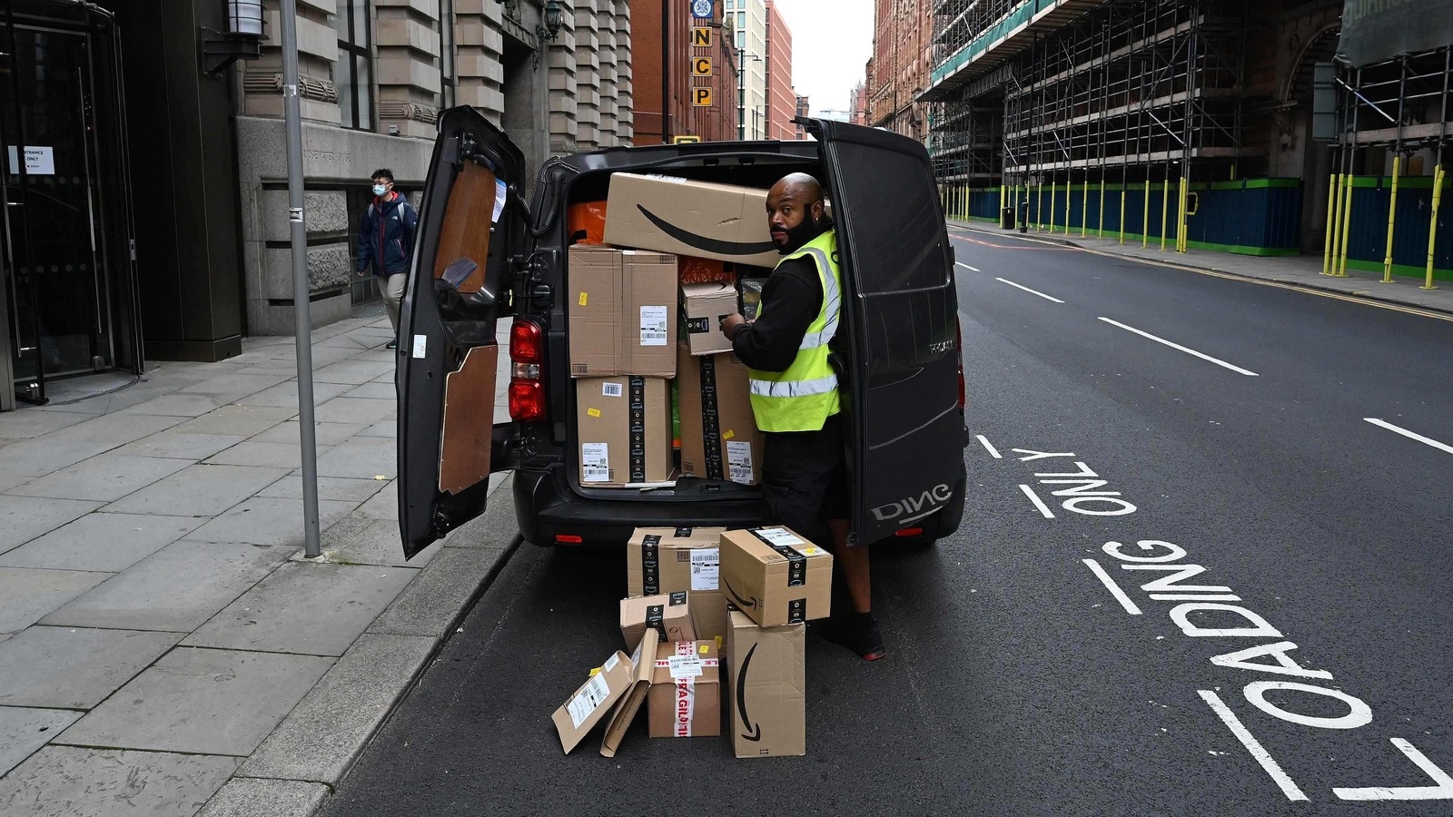 A delivery driver unloads Amazon-branded boxes in Manchester, northwest England. A delivery driver unloads Amazon-branded boxes in Manchester, northwest England.