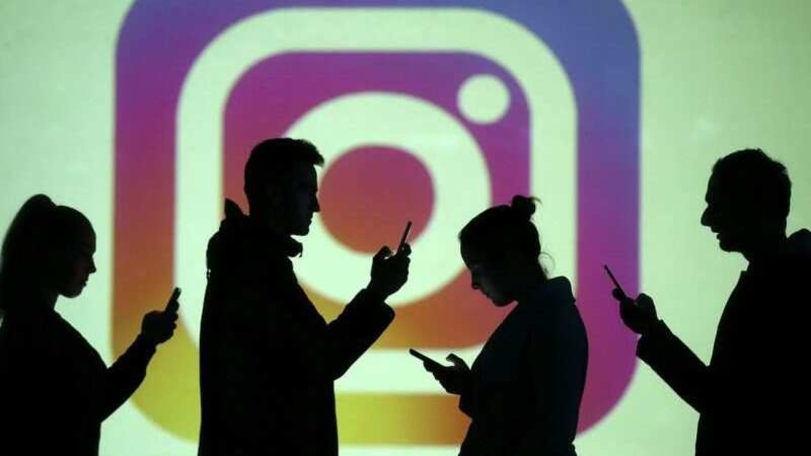 Silhouettes of mobile users are seen next to a screen projection of the Instagram logo in this picture illustration taken March 28, 2018. REUTERS/Dado Ruvic/Illustration/File Photo