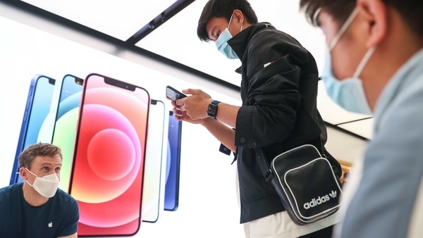 A customer wearing a protective mask tries out an Apple Inc. iPhone 12 Pro Max at the Apple flagship store during a product launch event in Sydney, Australia. 