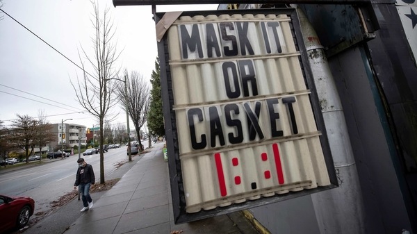 A sign regarding mask use to help curb the spread of COVID-19 hangs outside a business in Vancouver, British Columbia.