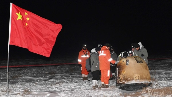 Researchers work around Chang'e-5 lunar return capsule carrying moon samples next to a Chinese national flag, after it landed in northern China's Inner Mongolia Autonomous Region, December 17, 2020. 